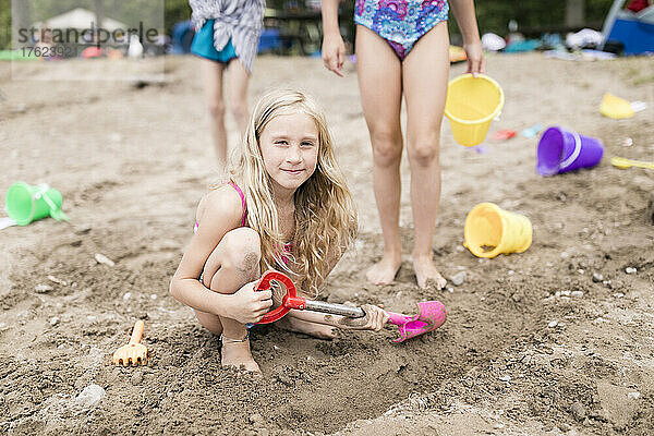 Mädchen mit Strandspielzeug spielen im Sand am Strand