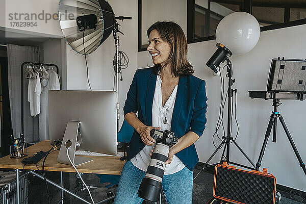 Lächelnder Fotograf hält Kamera im Studio
