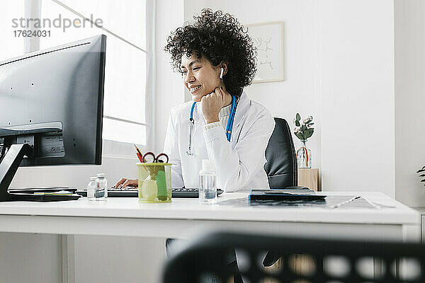 Arzt sitzt mit der Hand am Kinn am Desktop-PC in der Klinik