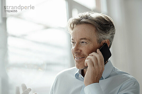 Smiling businessman talking on mobile phone in office