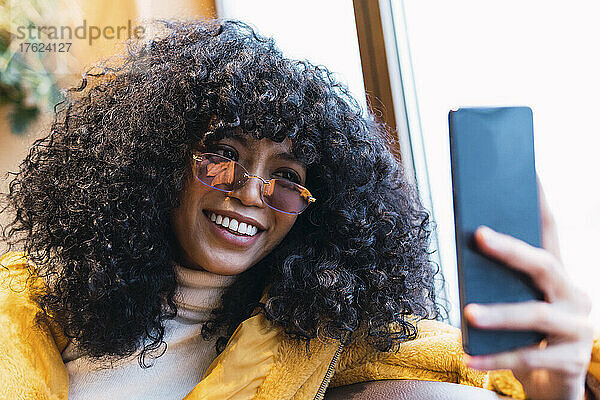 Lächelnde Frau mit Sonnenbrille  die ein Selfie mit dem Smartphone macht