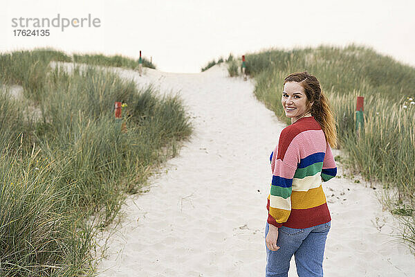Lächelnde schöne junge Frau  die auf Sand geht