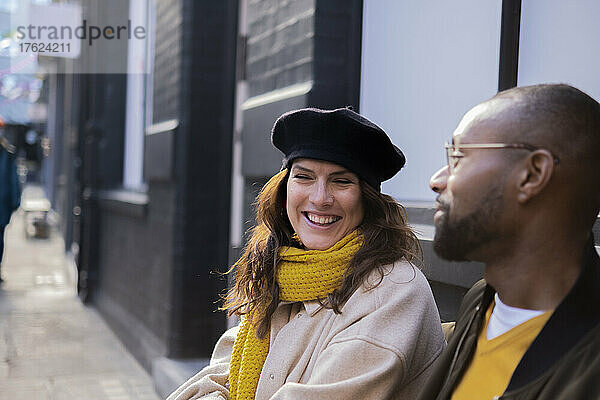 Mann schaut glückliche Frau mit Baskenmütze an