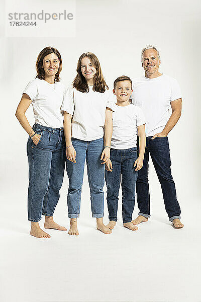 Smiling family standing against white background at studio