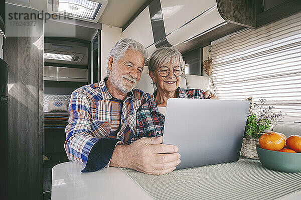 Lächelndes älteres Paar benutzt Laptop im Wohnmobil