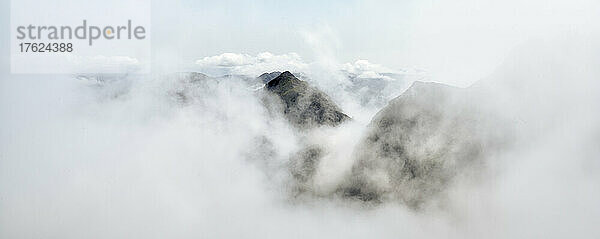 Scenic view of mountain peak seen through clouds