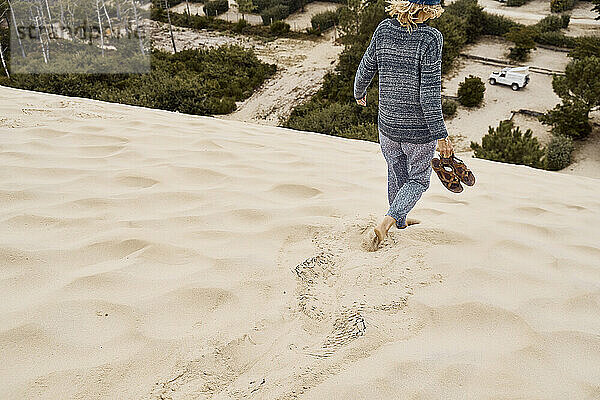 Tourist mit Schuhen läuft im Urlaub auf Sanddüne