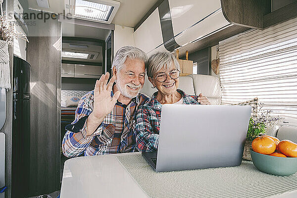 Glückliches älteres Paar winkt per Videoanruf über Laptop im Wohnmobil