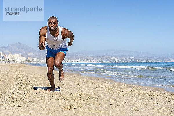 Sportler läuft an einem sonnigen Tag am Strand