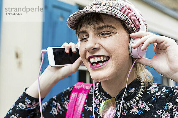 Happy young woman listening to music through headphones