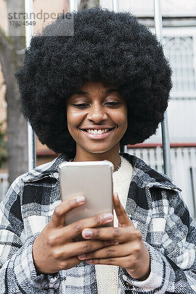 Glückliche Afro-Frau  die Textnachrichten über das Smartphone sendet