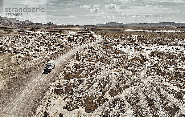 Auto fährt durch Wüstenstraße in der Landschaft bei Bardenas Reales  Spanien