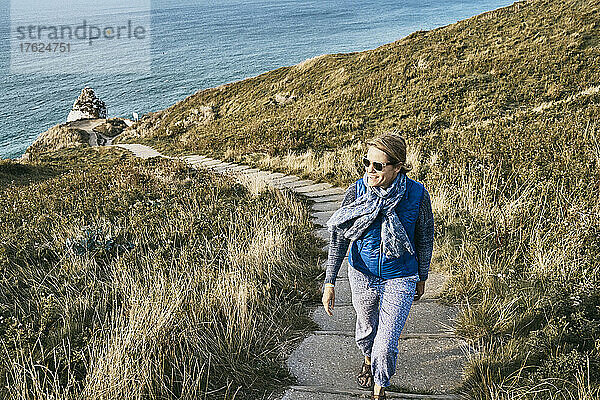 Frau geht im Urlaub auf dem Weg am Meer entlang