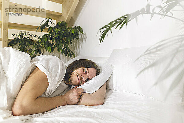 Smiling man resting on bed at home