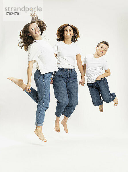 Mutter mit Kindern springt vor weißem Hintergrund