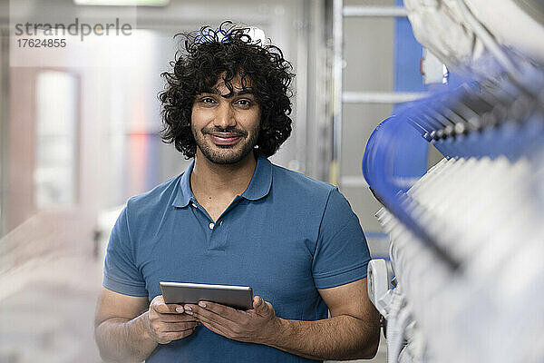 Lächelnder Techniker hält Tablet-PC in der Fabrik