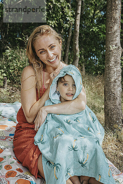 Lächelnde Mutter trocknet Sohn mit Handtuch am Seeufer