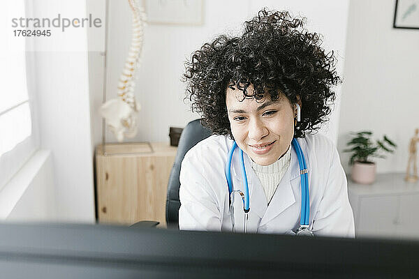 Arzt mit lockigem Haar  der in einer medizinischen Klinik arbeitet