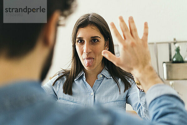 Frau streckt die Zunge heraus und gibt ihrem Freund zu Hause ein High-Five