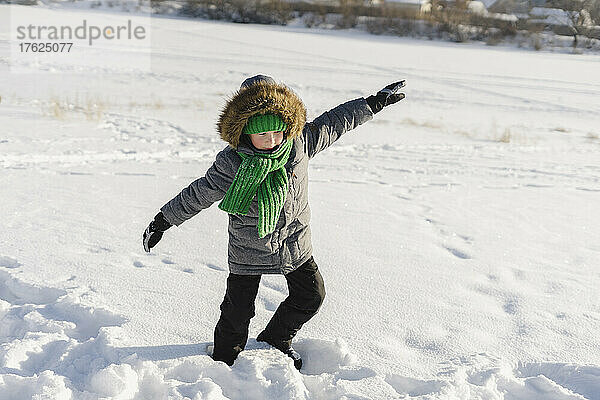 Boy with warm clothing having fun in snow