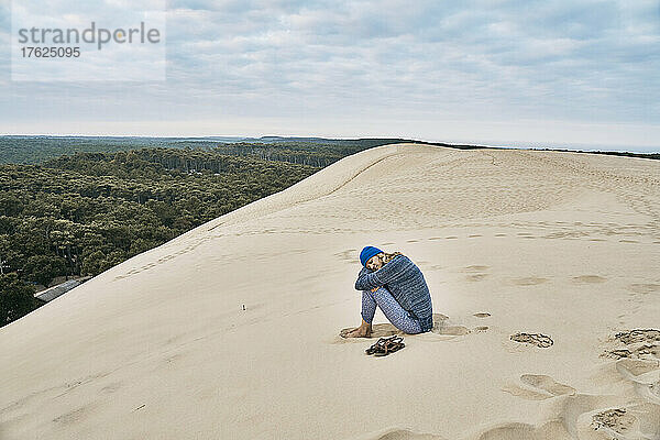 Frau sitzt im Urlaub auf Sanddüne