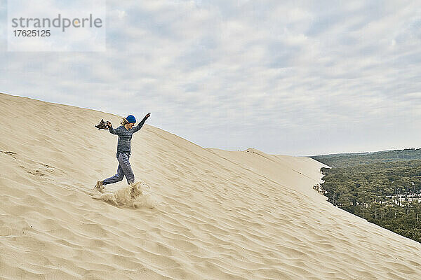 Cheerful woman running on sand dune