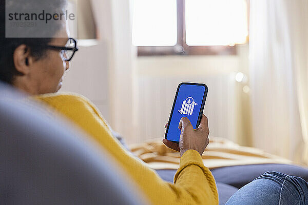 Woman using home automation app on smart phone in living room