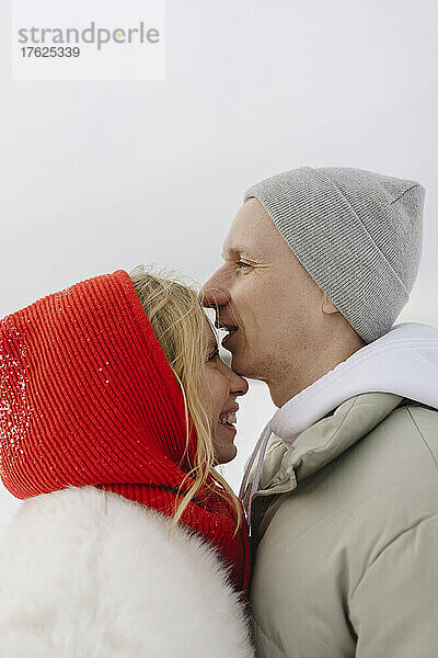 Smiling man wearing knit hat standing with blond girlfriend in winter