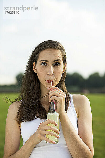 Junge Frau trinkt Limonadensaft in der Natur