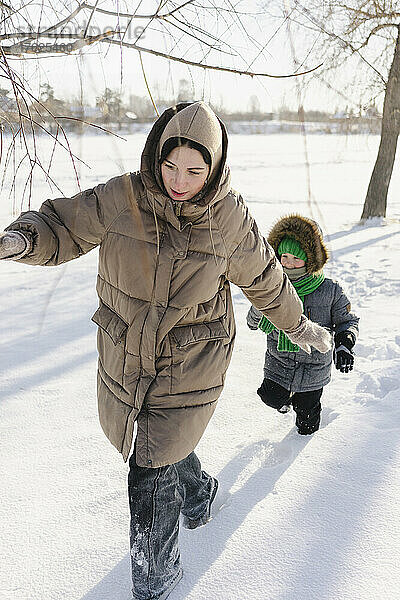 Sohn und Mutter in warmer Kleidung gehen auf Schnee