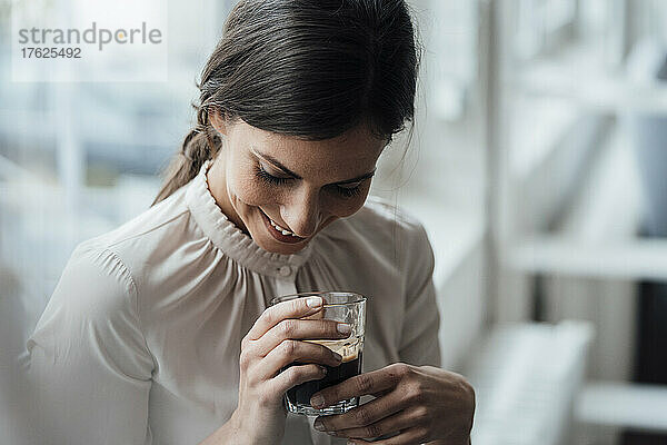 Lächelnde Geschäftsfrau hält Kaffeetasse im Büro