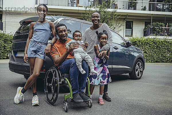 Fröhlicher behinderter Vater mit Familie im Auto