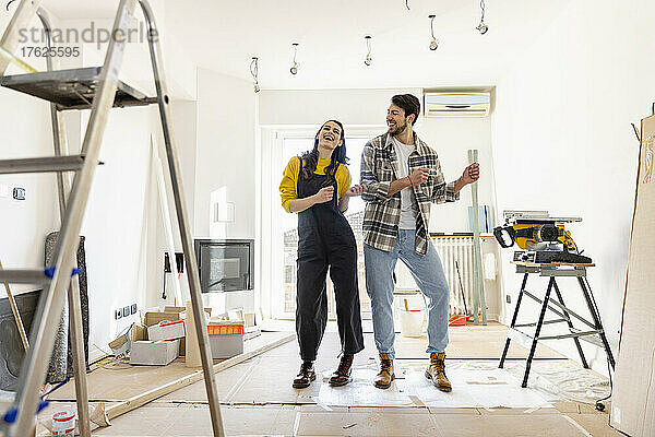 Fröhliches Paar renoviert sein Zuhause und tanzt im Wohnzimmer