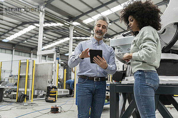 Ingenieur zeigt dem Entwickler in der Fabrik einen Tablet-PC