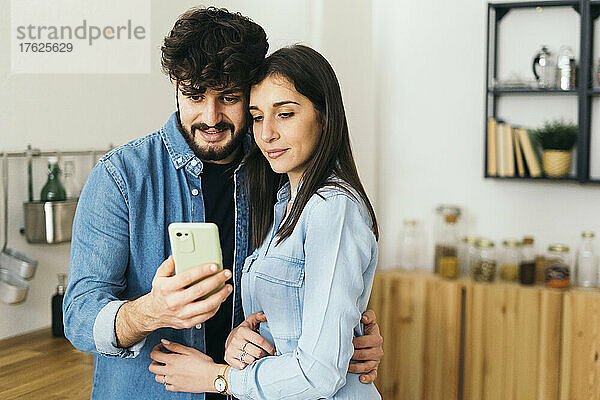 Junges Paar macht Selfie mit dem Handy in der heimischen Küche