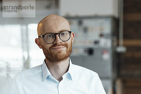 Smiling young bald working man wearing eyeglasses in office