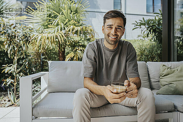 Happy man holding coffee cup sitting at lounge
