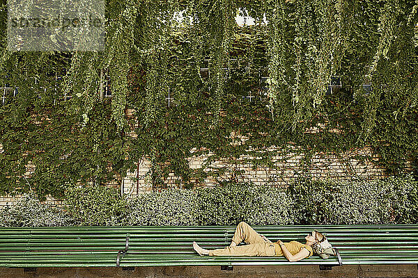 Woman lying on bench in park
