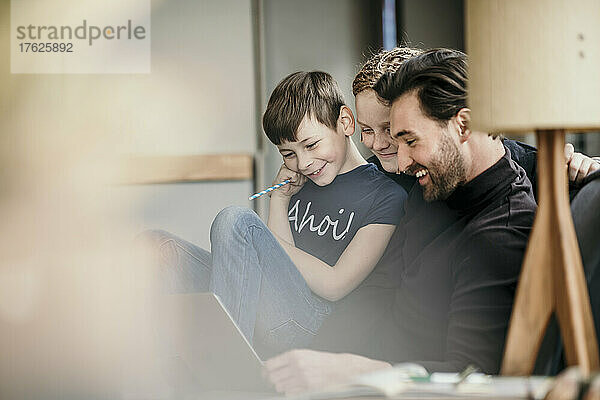 Glücklicher Mann mit Söhnen  die zu Hause Laptop benutzen