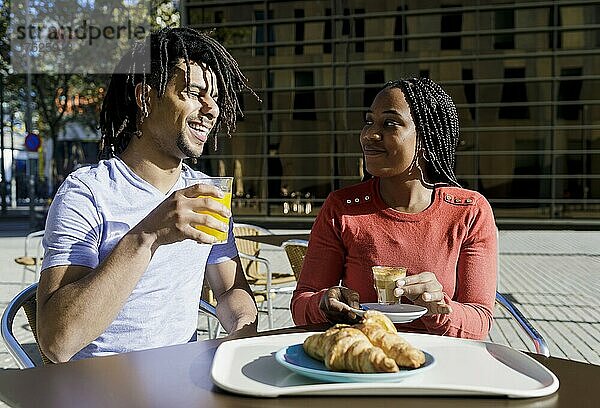 Lächelnder Mann und Frau beim Frühstück im Straßencafé