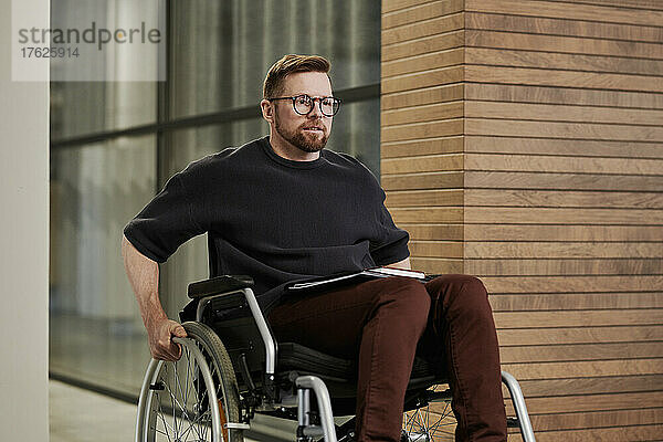 Behinderter Geschäftsmann im Rollstuhl  der im Büro arbeitet