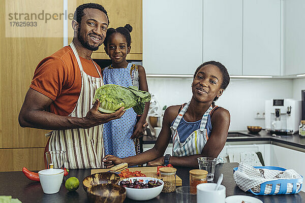Lächelnder Vater mit seinen Töchtern in der heimischen Küche