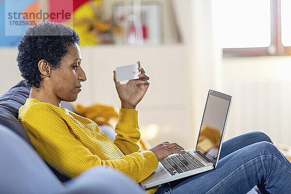 Frau mit Kreditkarte kauft zu Hause am Laptop online ein