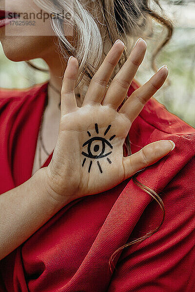Junge Frau zeigt Augenzeichen-Tätowierung auf ihrer Hand