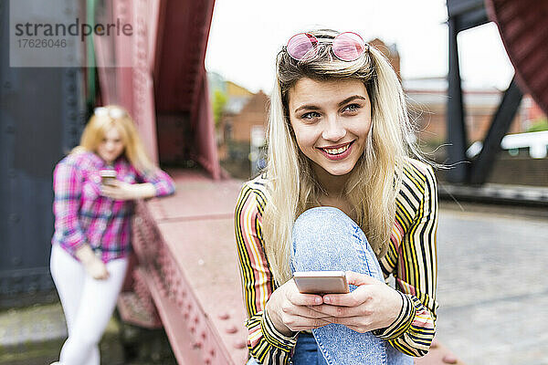 Happy teenager wearing sunglasses holding smart phone