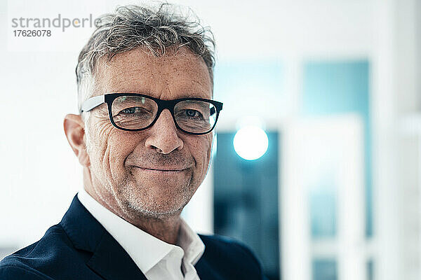 Lächelnder Geschäftsmann mit Brille im Büro