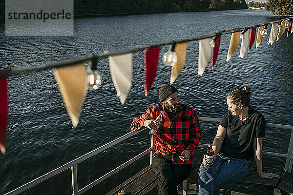 Friends holding beer bottles sitting on boat deck
