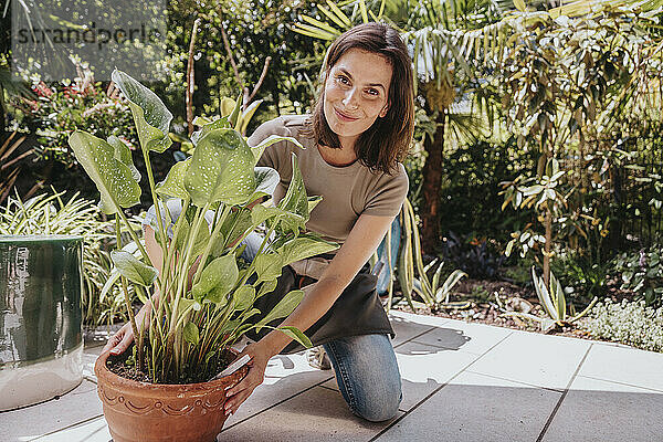 Lächelnder Gärtner hält Topfpflanze im Garten