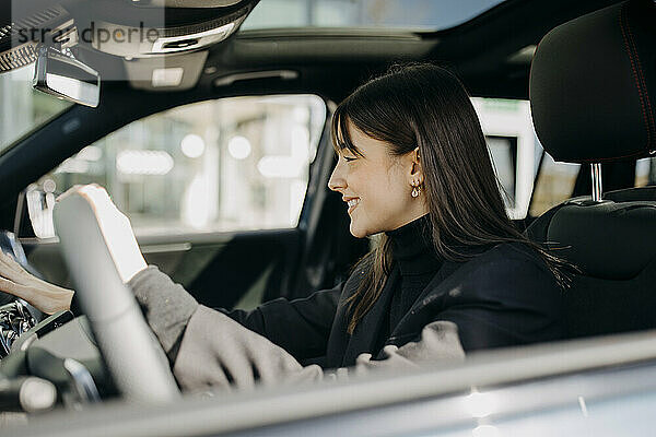 Lächelnde Geschäftsfrau  die das Bedienfeld eines Elektroautos nutzt