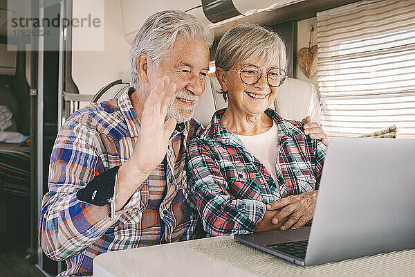 Lächelnder älterer Mann und Frau bei Videoanruf auf Laptop im Wohnmobil